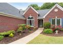 Close-up of a brick home's entrance with colorful flower beds, a walkway, and manicured shrubs at 1031 Ludwick Way, Lawrenceville, GA 30046