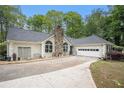 A view of the side of the home showing a stone chimney and manicured front yard at 110 Emerald Dr, Mcdonough, GA 30253