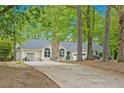 A view of the home on a wooded lot, with a stone chimney and well-kept lawn at 110 Emerald Dr, Mcdonough, GA 30253