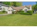 Ranch-style home featuring a two-car garage, manicured lawn, and mature shrubbery at 1220 Paddocks Way, Powder Springs, GA 30127