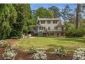 A well-maintained backyard features a two-story home with a deck and patio surrounded by lush greenery and flowers at 4220 Club Ne Dr, Atlanta, GA 30319
