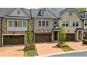 Attractive townhome featuring a two-car garage, lush landscaping, and tasteful stone details at 126 Abbington River Ln, Atlanta, GA 30339