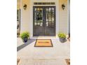 Welcoming front door with glass panels, flanked by potted flowers and a 'Welcome' mat on a covered porch at 2175 Eagle Trce, Cumming, GA 30040