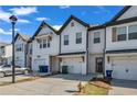 A row of townhomes featuring white siding, garages, black trim and timber accents creating a cohesive community aesthetic at 4142 Spring Valley Cir # 65, Tucker, GA 30084