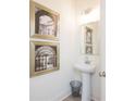 Stylish half bathroom featuring a modern pedestal sink, decorative mirror, and elegant wall art at 1567 Aiden Way # 34, Conyers, GA 30013