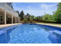 Backyard pool surrounded by concrete decking and lush landscaping, perfect for outdoor relaxation and entertaining at 526 Lost Creek Dr, Woodstock, GA 30188
