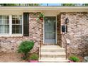 Close-up of the front entrance with brick facade, a storm door, and hanging plants at 2404 Northlake Ct, Atlanta, GA 30345