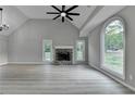 Open living room with vaulted ceiling, stone fireplace, large picture window and fan at 5825 Rolling Oaks Dr, Cumming, GA 30040