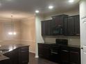 Well-equipped kitchen with dark cabinets, granite countertops, stainless steel appliances, and hardwood floors at 142 Susie Creek Ln, Villa Rica, GA 30180