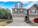 Inviting townhome featuring a two-car garage, charming facade, and well-kept front yard at 2722 Sardis Chase Ct, Buford, GA 30519