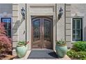 Elegant front entry with ornate double doors, flanked by potted plants, wall sconces, and detailed stonework at 18 Rose Gate Ne Dr, Atlanta, GA 30342