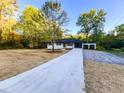 Ranch-style home with a long concrete driveway leading to a white-painted brick home with an attached carport at 7817 Mattie Mccoy Ln, Winston, GA 30187