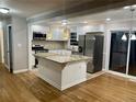 Open-concept kitchen with granite island, stainless steel appliances, and sleek white cabinets at 1607 Hillview Ave, Jonesboro, GA 30236