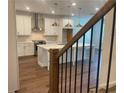 Bright, modern kitchen featuring an island, stainless hood, and hardwood flooring at 5022 Buice Crest Court, Buford, GA 30518