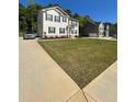 A two-story home is featured on a sunny day, showcasing a well-manicured lawn, and neighboring houses at 205 Sullivan St, Hampton, GA 30228