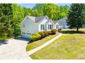 View of the home's side and garage entrance, complete with a well-kept lawn and blooming bushes at 4066 Harvest Ridge Dr, Douglasville, GA 30135