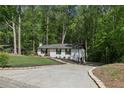 This home boasts a long driveway, pristine landscaping, and lush surrounding trees at 151 John Christopher Dr, Alpharetta, GA 30009