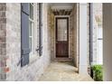 Inviting front porch with stone flooring, brick walls, and a wooden door with glass inserts at 3318 Monceau Way, Roswell, GA 30075