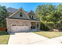 Attractive home featuring a brick facade, two-car garage, long driveway, and well-maintained landscaping at 6424 Barker Station Walk, Sugar Hill, GA 30518