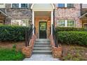 Inviting brick and stone townhome entrance with wrought iron railing leading up to a black front door at 1233 Ashford Creek Ne Park, Atlanta, GA 30319