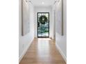 Hallway view with wooden floors, art, and a black door with a wreath at 1305 Old Woodbine Rd, Atlanta, GA 30319