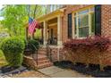 Charming front porch with brick steps, black railings, lush landscaping, and an American flag at 107 Estates At The Lake Dr, Canton, GA 30114