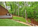 Landscaped backyard, perfect for entertaining, features a stone patio and a lush grassy area surrounded by mature trees at 1250 Northcliff Trce, Roswell, GA 30076