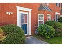 Close-up of a brick townhouse entry with manicured bushes and security lighting at 5679 Windfall Ln, Lithonia, GA 30058