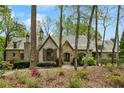 Stunning stone and brick home with a uniquely designed roof, complemented by natural landscaping at 105 Kingston Mnr, Atlanta, GA 30342