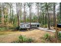 Exterior view of a single story home and driveway nestled among mature trees in a quiet neighborhood at 5000 Northland Sw Rd, Mableton, GA 30126