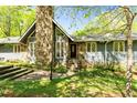 Inviting home featuring a stone chimney, ample windows, and a well-manicured lawn at 175 Flat Creek Ct, Fayetteville, GA 30214