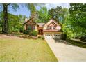 Two-story home with Tudor architecture, featuring a two-car garage, mature trees, and a lush green front lawn at 2261 Byron Sw Ct, Marietta, GA 30064