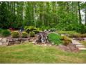 Lush backyard with tiered landscaping, featuring a beautiful waterfall and ample greenery at 104 Fairway Overlook, Woodstock, GA 30188