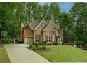 Charming brick home featuring a well-kept lawn, arched doorway, and convenient driveway access at 104 Fairway Overlook, Woodstock, GA 30188