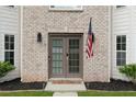 Close up of beautiful double front doors, brick facade, an American flag, and well-manicured landscaping at 160 Fieldstone Dr, Powder Springs, GA 30127