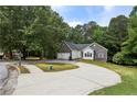 Well-kept one-story home featuring a stone facade, wide driveway, and mature trees at 1945 Grayson Oaks Ct, Lawrenceville, GA 30045
