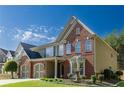 This brick and siding home features a manicured lawn, a two-car garage, and is full of natural light at 5424 Landsdowne Ct, Cumming, GA 30041