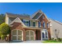 This two-story brick and siding home has a well-manicured lawn and a convenient two-car garage at 5424 Landsdowne Ct, Cumming, GA 30041