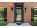 Elegant front door with black trim, brick facade, and stylish exterior lighting at 5790 Heards Forest Dr, Atlanta, GA 30328