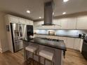 Modern kitchen with stainless steel appliances, white cabinets, black countertops, and hardwood floors at 4130 Overland Dr, Roswell, GA 30075