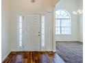 Bright foyer features a decorative glass sidelight door, hardwood floors, and an arched window at 811 Betsy Ross Trl, Hampton, GA 30228