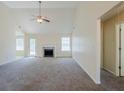 Spacious living room with vaulted ceilings, plush carpeting, a ceiling fan, and a cozy fireplace at 811 Betsy Ross Trl, Hampton, GA 30228
