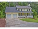 Charming yellow two-story home featuring a two-car garage and a covered front porch at 3899 Leach Rd, Snellville, GA 30039