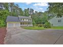 Traditional yellow home with a two-car garage and inviting front porch in a wooded setting at 3899 Leach Rd, Snellville, GA 30039