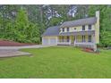Inviting yellow home boasts a two-car garage, covered porch, and a lush front lawn at 3899 Leach Rd, Snellville, GA 30039