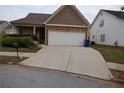 Charming home featuring a two-car garage, stone accents, and well-maintained landscaping at 115 Catlyn Ct, Riverdale, GA 30296
