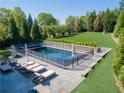 Backyard pool area featuring a fenced-in pool, lounging chairs, and ample green space for outdoor enjoyment at 2199 Tayside Nw Xing, Kennesaw, GA 30152