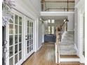 Bright foyer boasts hardwood floors, staircase, and grand entrance with glass-paneled double doors at 5093 Heartland Trl, Hoschton, GA 30548
