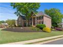 Charming two-story brick home features a manicured lawn, mature trees, and traditional design at 605 Tatum Ct, Alpharetta, GA 30022