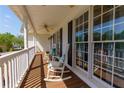 Inviting front porch with white rocking chairs, ceiling fan, and ample natural light from the large windows at 208 Wellington Walk, Douglasville, GA 30134
